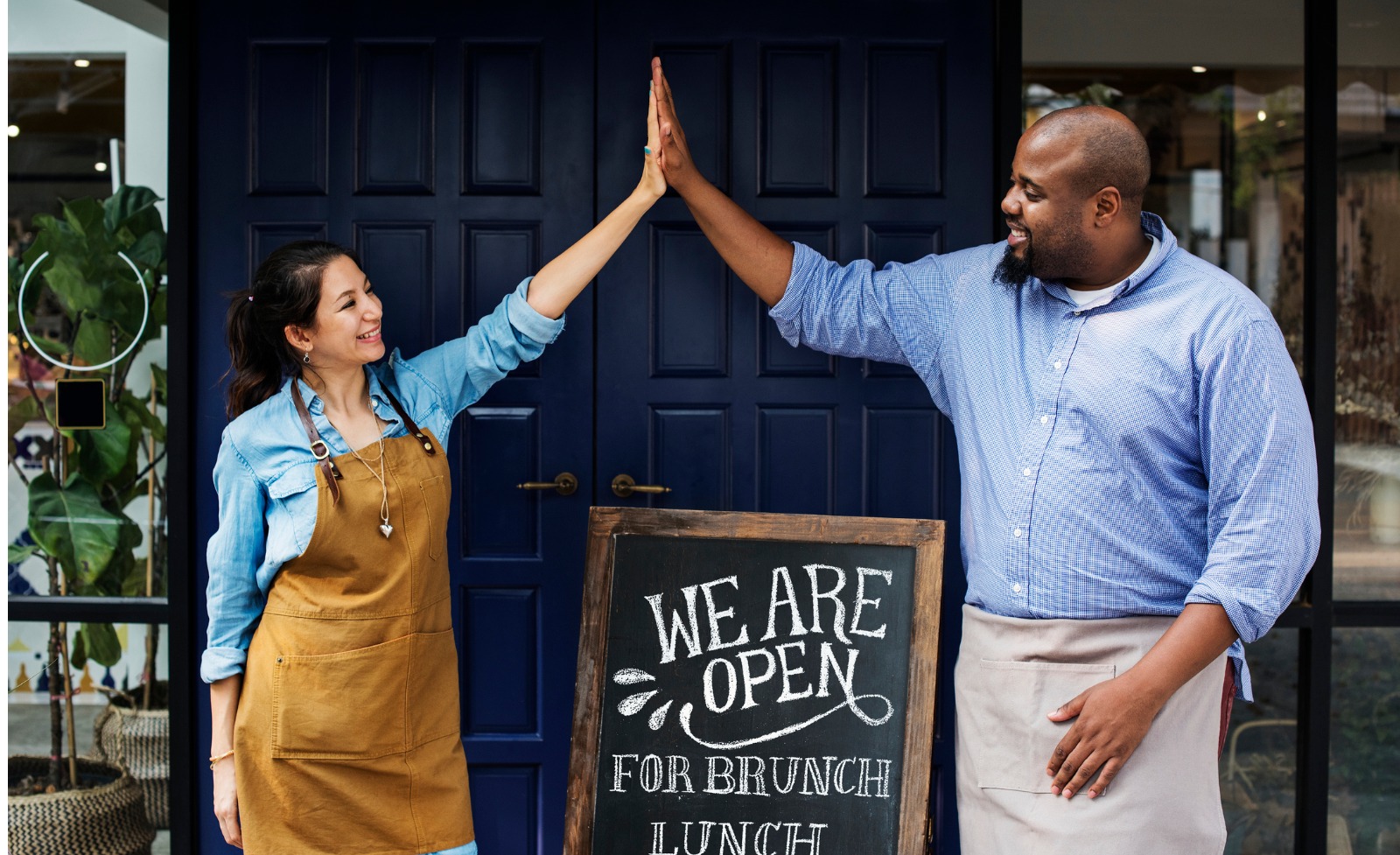 Two people high five after opening business.