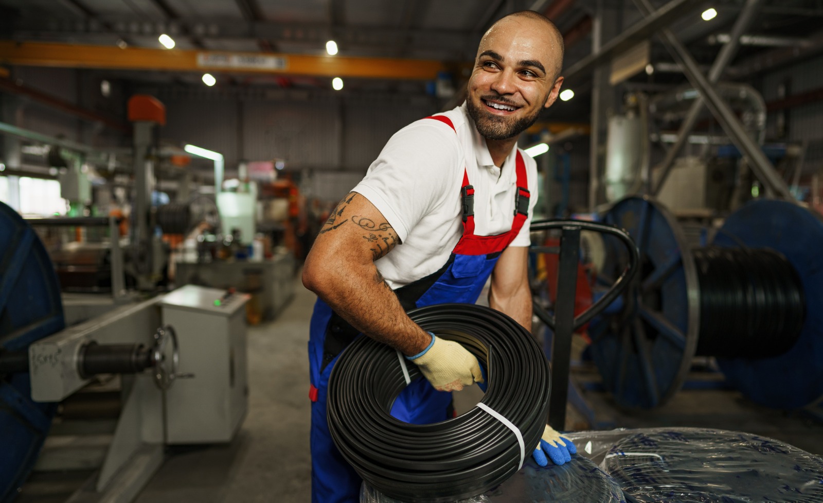 A smiling employee holding equipment on a shop floor.
