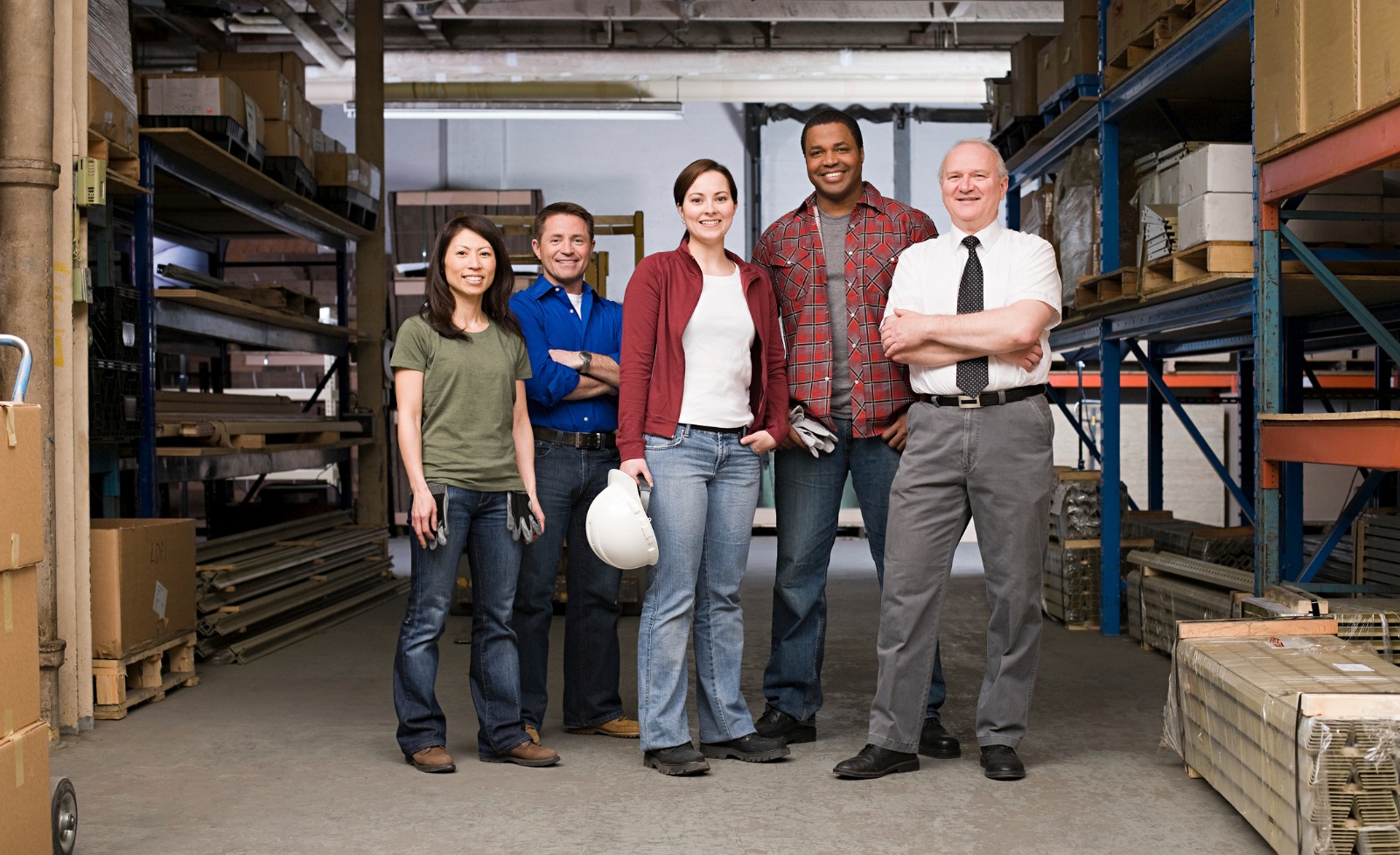 Team of employees and manager smiling in warehouse setting.