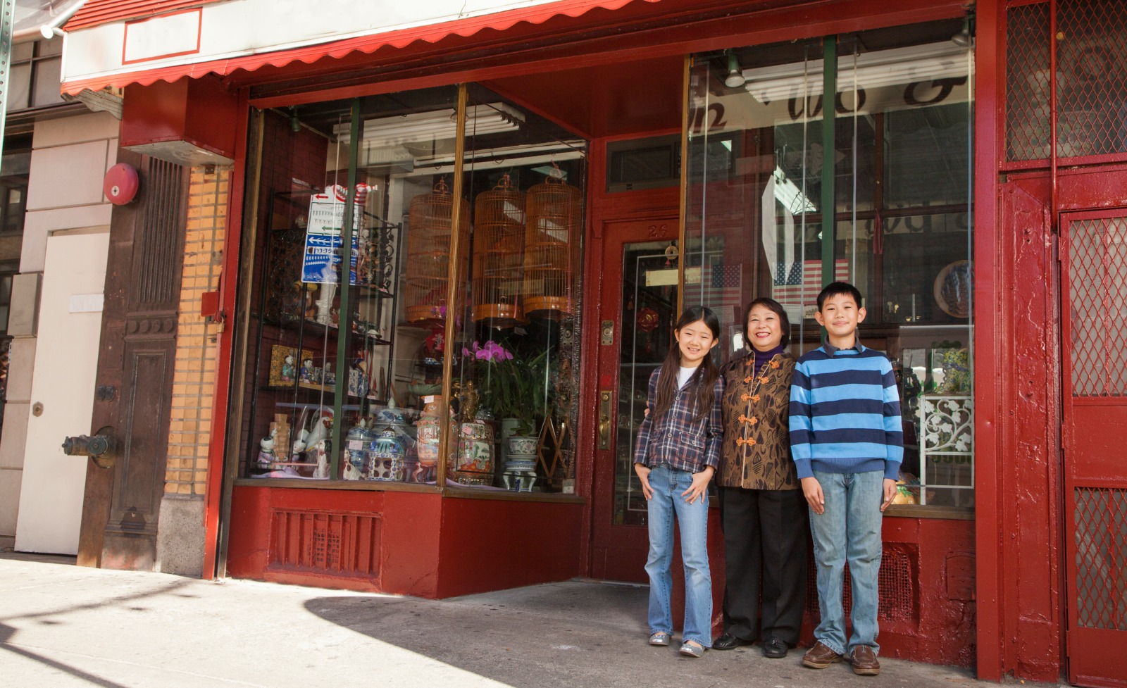 A smiling Asian family standing in front of a storefront.